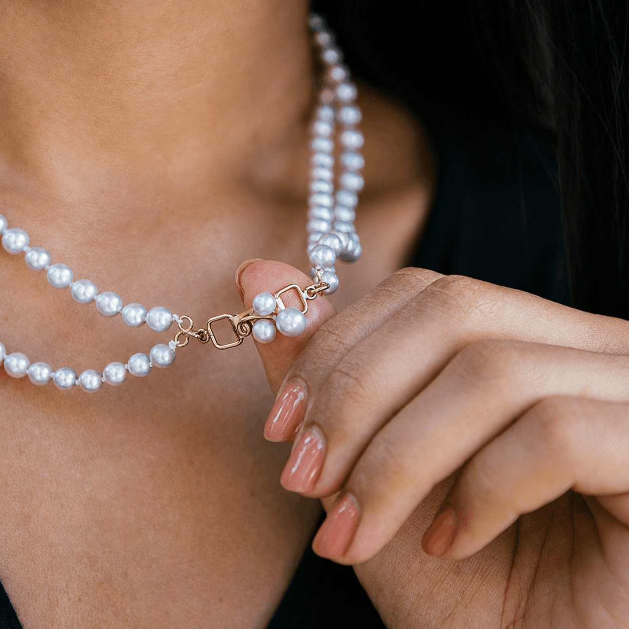 Mings of Honolulu baroque blue akoya pearl necklace with a gold clasp being adjusted by a hand