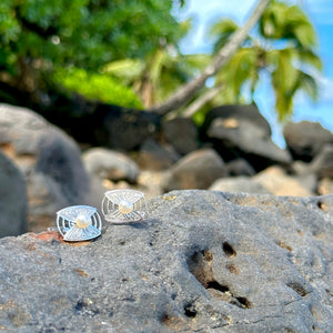 Sterling silver engraved cufflinks with white akoya pearls on lava rocks with palm trees in the background in Hawaii.